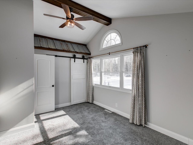 unfurnished bedroom with lofted ceiling with beams, a barn door, and carpet flooring