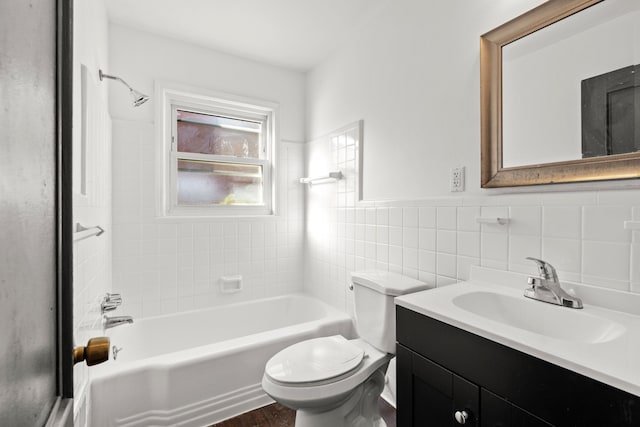 full bathroom with tile walls, vanity, tiled shower / bath combo, and toilet