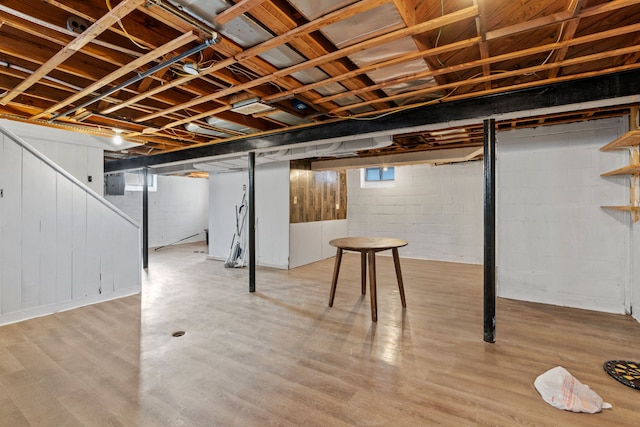 basement featuring electric panel and light hardwood / wood-style floors