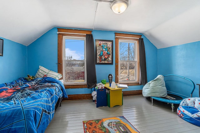 bedroom featuring multiple windows, baseboards, lofted ceiling, and hardwood / wood-style floors