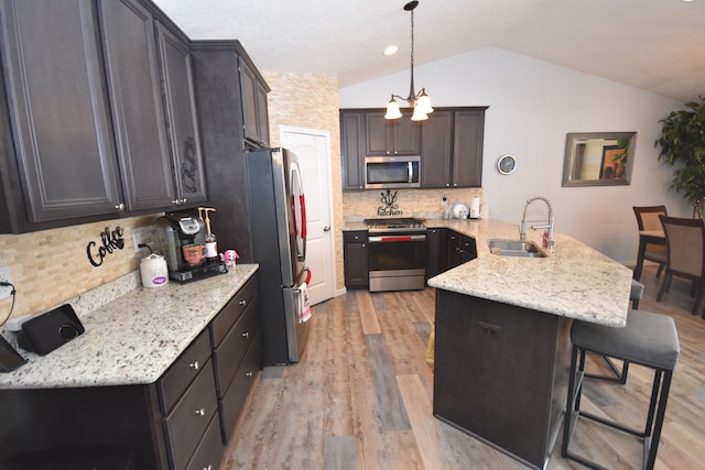 kitchen with pendant lighting, sink, a breakfast bar area, appliances with stainless steel finishes, and kitchen peninsula