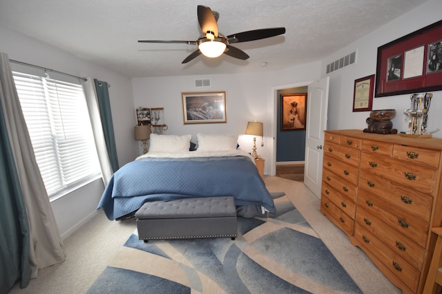 carpeted bedroom featuring a textured ceiling and ceiling fan