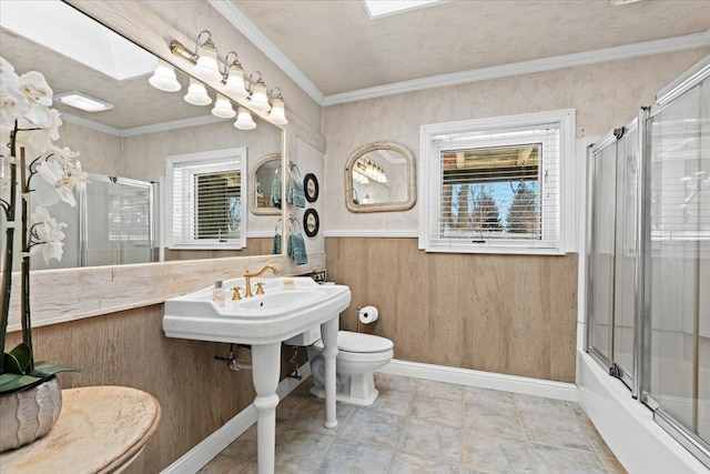 bathroom featuring a skylight, enclosed tub / shower combo, crown molding, and toilet