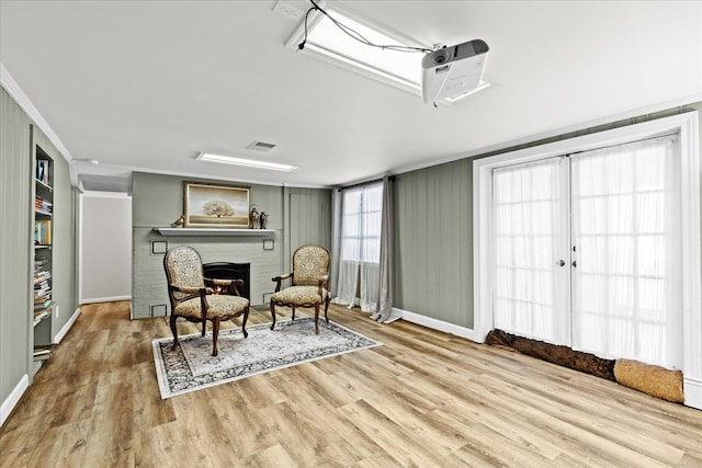 living area with crown molding and light hardwood / wood-style flooring