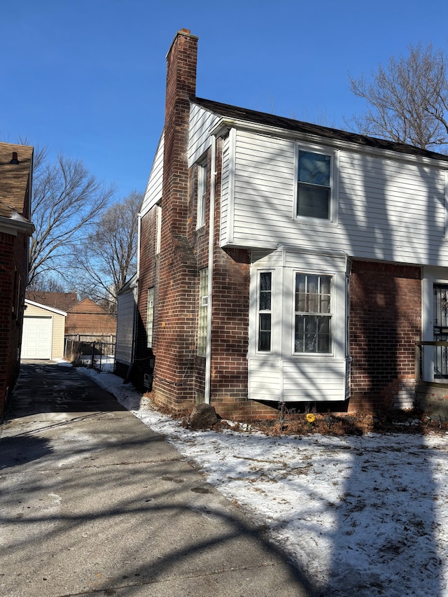 view of side of property featuring an outbuilding, brick siding, and a chimney