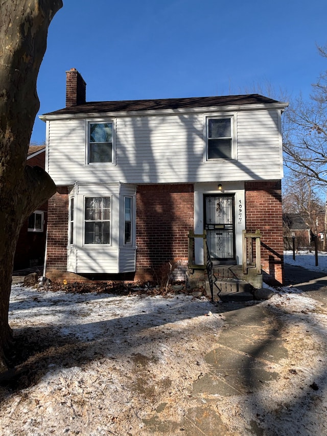 colonial house with a chimney and brick siding