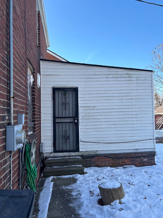 snow covered property entrance featuring brick siding