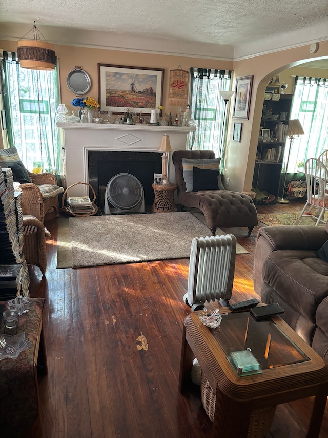 living area featuring arched walkways, hardwood / wood-style floors, a textured ceiling, and a fireplace