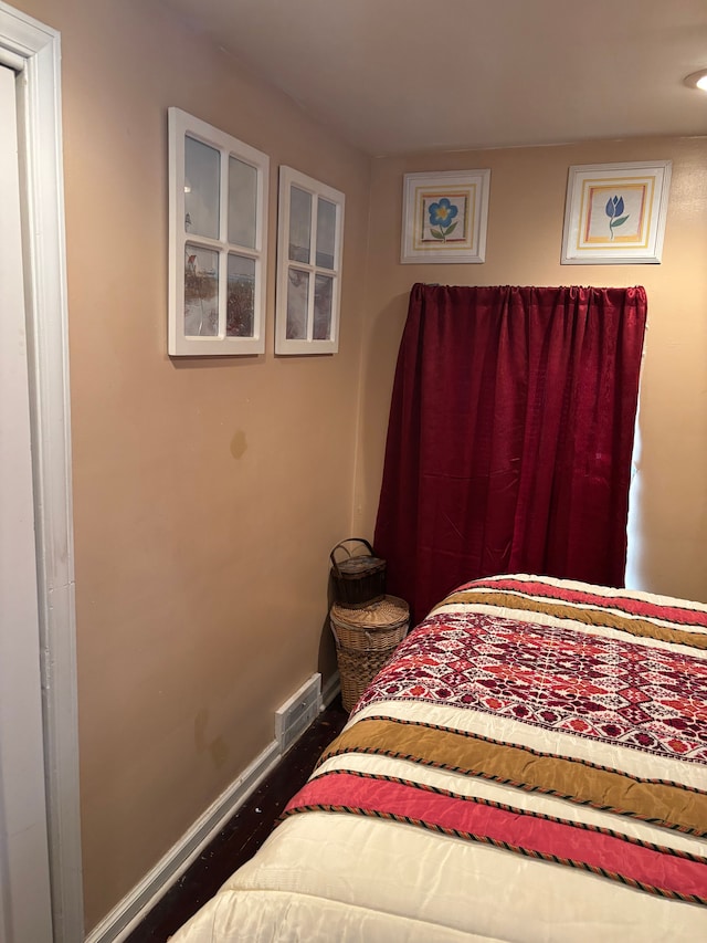 bedroom featuring visible vents, baseboards, and wood finished floors