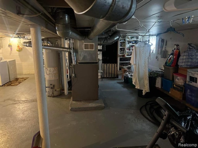 basement featuring water heater, heating unit, and washer and dryer