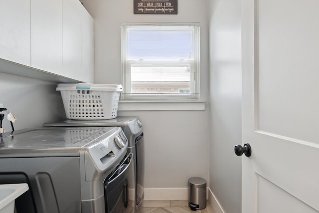 laundry room featuring cabinet space, baseboards, and washer and clothes dryer