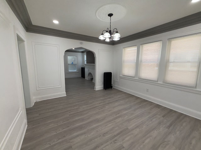 unfurnished dining area with an inviting chandelier, crown molding, and dark wood-type flooring