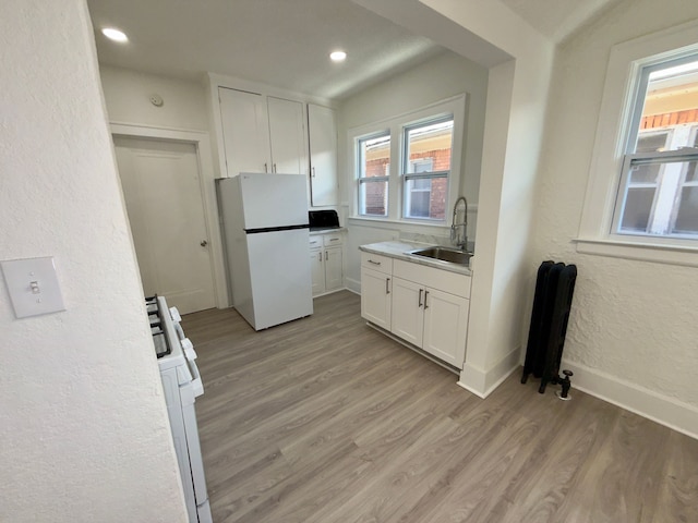 kitchen featuring white cabinetry, white appliances, sink, and light wood-type flooring