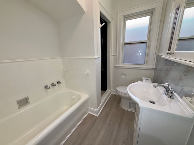 bathroom featuring vanity, hardwood / wood-style flooring, a tub, and toilet