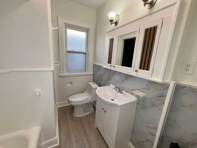 bathroom with toilet, tile walls, vanity, a bathtub, and hardwood / wood-style flooring