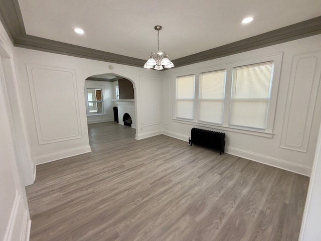 interior space featuring an inviting chandelier, radiator, ornamental molding, and hardwood / wood-style floors