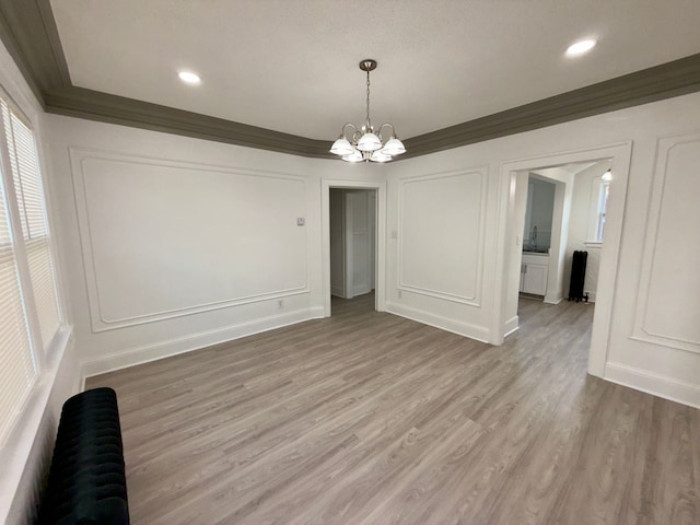 unfurnished dining area with crown molding, a chandelier, and hardwood / wood-style floors