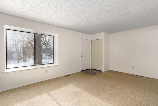 unfurnished room with carpet flooring and a textured ceiling