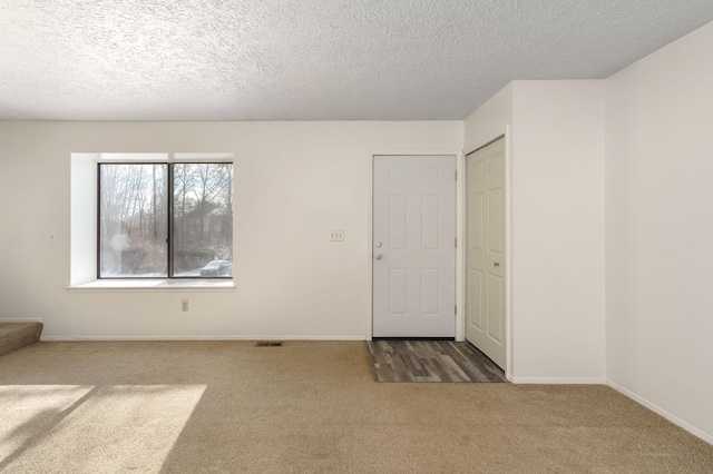 carpeted empty room with a textured ceiling