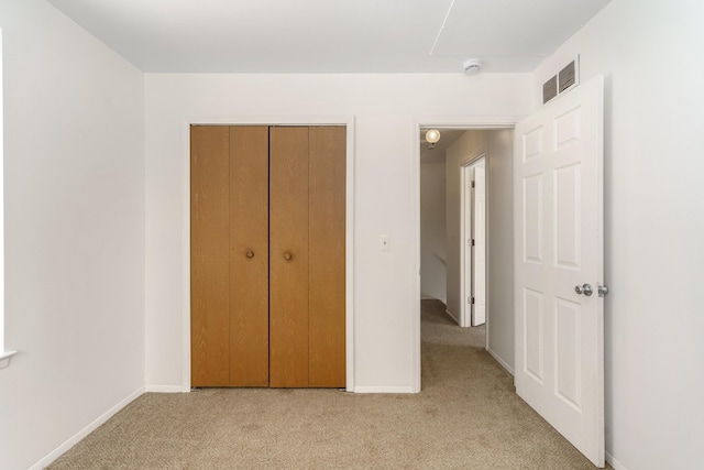 unfurnished bedroom with light colored carpet and a closet