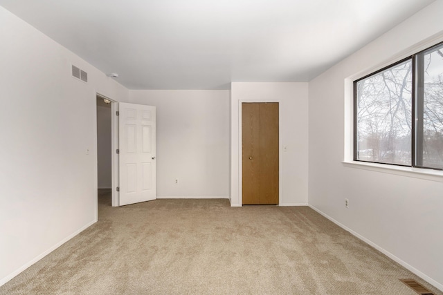 unfurnished bedroom featuring light carpet and a closet