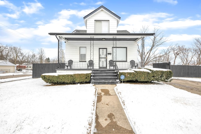 bungalow-style home featuring covered porch, a shingled roof, and fence