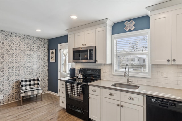 kitchen featuring white cabinetry, sink, black appliances, and a healthy amount of sunlight