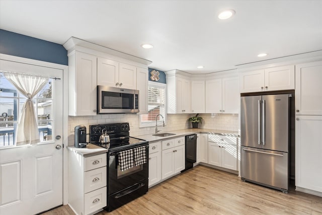 kitchen with sink, light hardwood / wood-style flooring, white cabinetry, tasteful backsplash, and black appliances