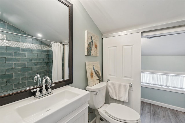 bathroom with lofted ceiling, vanity, wood-type flooring, and toilet