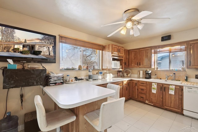 kitchen featuring plenty of natural light, sink, white appliances, and kitchen peninsula