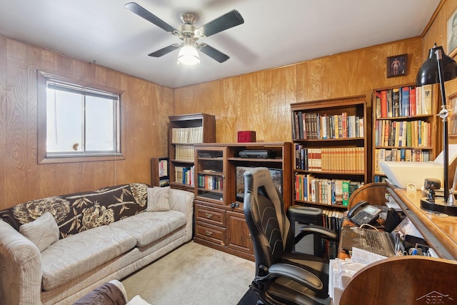 home office featuring ceiling fan, light colored carpet, and wooden walls