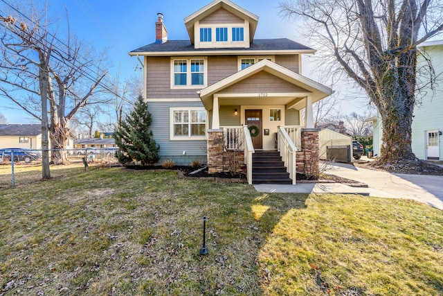 traditional style home featuring a front lawn, fence, covered porch, an outdoor structure, and a chimney