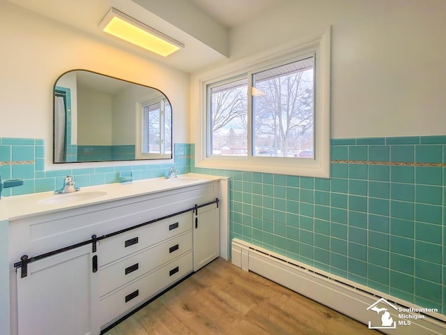 bathroom featuring a baseboard radiator, vanity, hardwood / wood-style floors, and tile walls