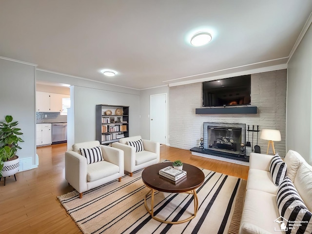 living room with crown molding, a large fireplace, and light hardwood / wood-style flooring