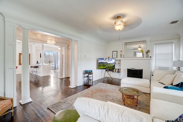 living room with dark hardwood / wood-style floors, ceiling fan, a fireplace, and decorative columns