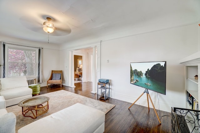 living room with radiator heating unit, decorative columns, dark hardwood / wood-style floors, and ceiling fan