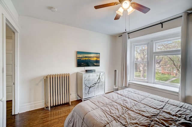 bedroom featuring dark wood-type flooring, radiator heating unit, and ceiling fan