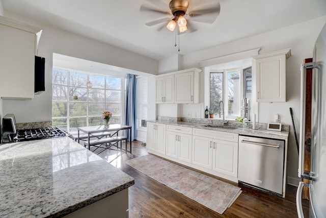 kitchen with light stone countertops, white cabinetry, appliances with stainless steel finishes, and sink