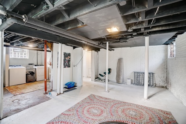 basement featuring brick wall and washer and clothes dryer