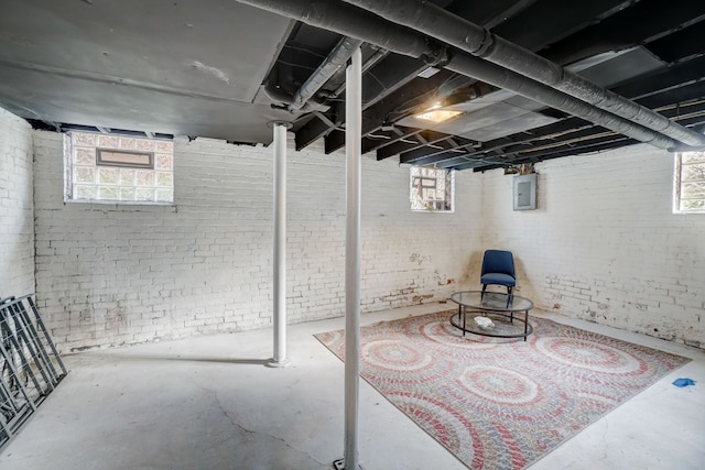 basement with brick wall, plenty of natural light, and electric panel