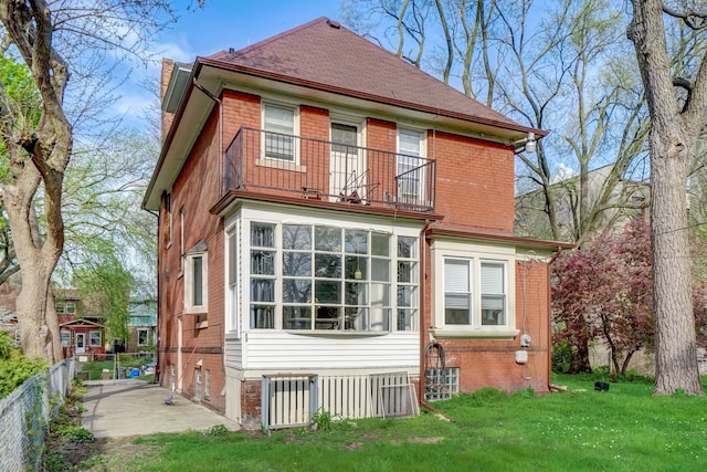 back of house with a lawn and a balcony