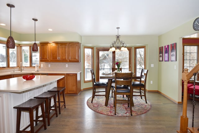 dining room featuring baseboards, dark wood-type flooring, plenty of natural light, and an inviting chandelier