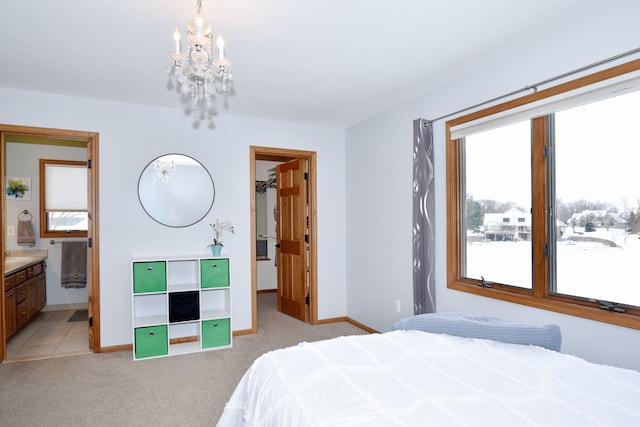 bedroom with a walk in closet, an inviting chandelier, light carpet, connected bathroom, and baseboards