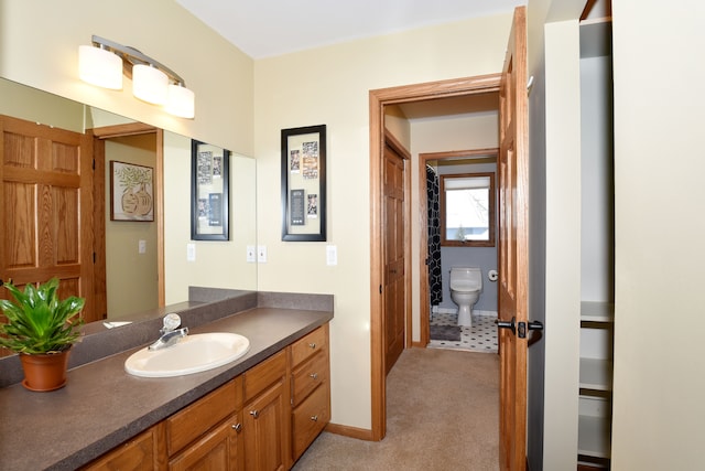 bathroom with toilet, baseboards, and vanity