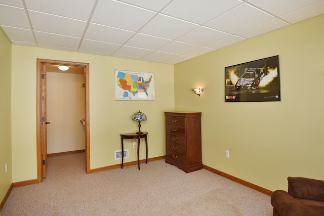 living area with light carpet, a drop ceiling, visible vents, and baseboards