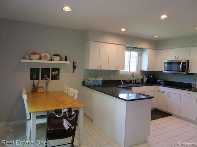 kitchen featuring backsplash, sink, kitchen peninsula, and white cabinets