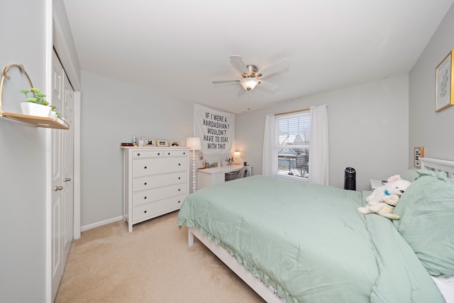 bedroom with ceiling fan, light colored carpet, and a closet