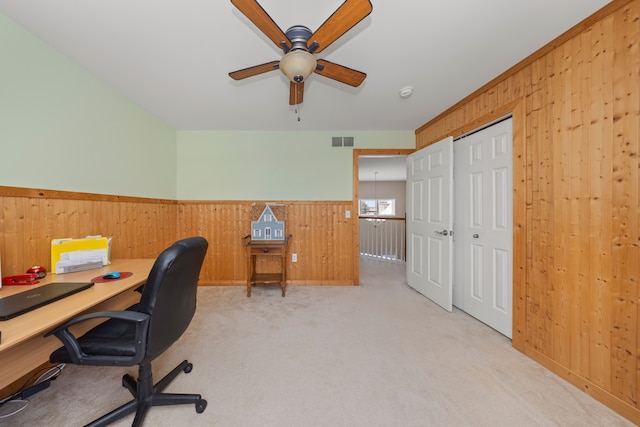 carpeted office featuring ceiling fan and wooden walls