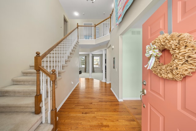 entryway featuring a towering ceiling and light wood-type flooring