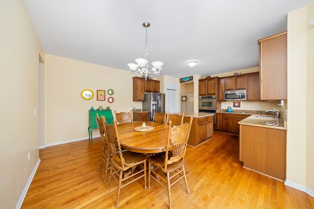 dining room with sink, a notable chandelier, and light hardwood / wood-style floors